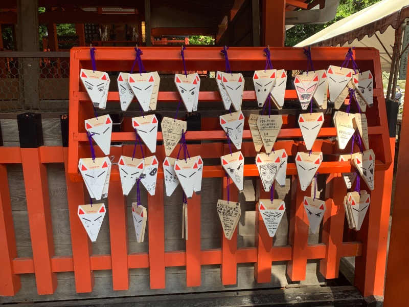 making wishes on fox cutouts at fushimi inari
